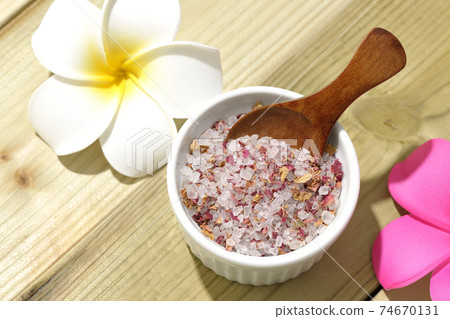 A wooden spoon is stuck in the bath salt in the bowl. 74670131