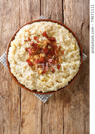 Tasty Estonian mashed potatoes and barley with onions and bacon close-up in a plate. vertical top view Tasty Estonian mashed potatoes and barley with onions and bacon close-up in a plate. vertical top view 74671111