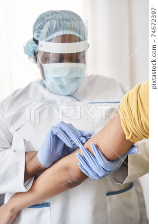 Nurse doing vaccination with serious expression Nurse doing vaccination with serious expression 74672397