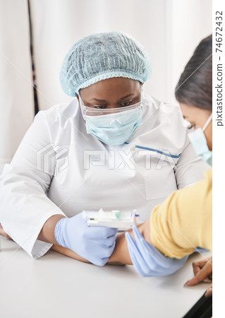 Nurse making injection to young brunette woman Nurse making injection to young brunette woman 74672432