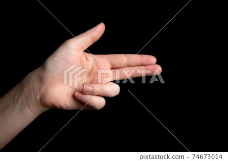 Person Holding symbolic gun with hand gesture, playing killing shooting weapons isolated on dark black background, symbolic gun concept 74673014