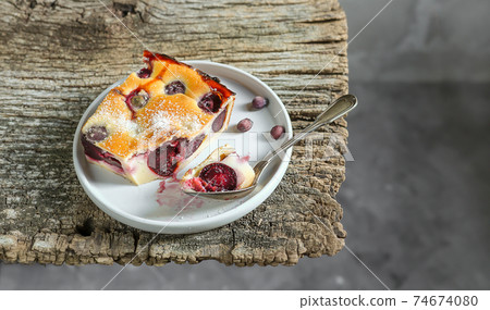 A slice of homemade clafoutis cherry pie - traditional french dessert in a gray plate 74674080