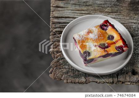 A slice of homemade clafoutis cherry pie - traditional french dessert in a gray plate 74674084