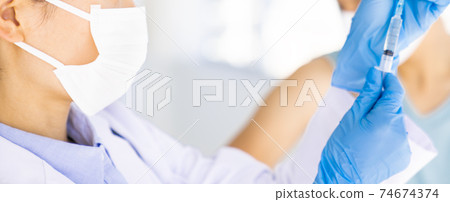 Doctor pulling vaccine from vial 74674374