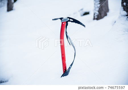 The ice ax is needed for climbing. Close-up of an ice ax in the snow. 74675597