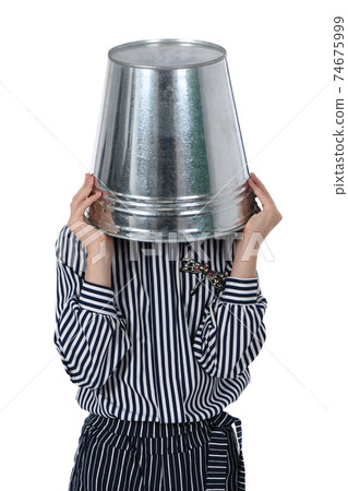 Young girl with metal bucket on head. Young girl with metal bucket on head. 74675999
