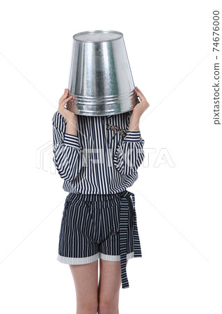 Young girl with metal bucket on head. Young girl with metal bucket on head. 74676000