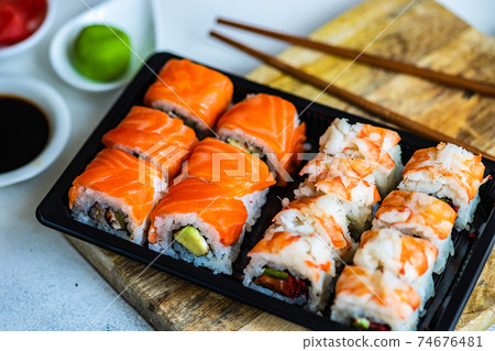 Sushi Set  with various sashimi, sushi rolls and tea  served on stone slate 74676481