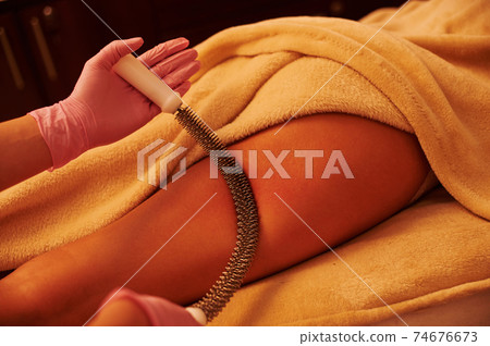 Closeup of young woman lying on massage table and receiving anti cellulite leg massage at SPA salon 74676673