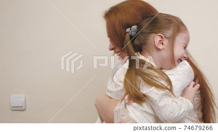 Little child hugs mom and laughs. Happy girl rejoices at mommy. A daughter and a woman are playing in the children's room. Mothers Day. Parents' love for kid. Upbringing on maternity leave. Family 74679266
