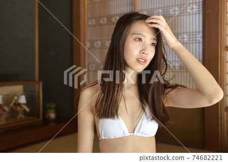 A smiling young woman in a white bikini relaxing in a Japanese-style room A smiling young woman in a white bikini relaxing in a Japanese-style room 74682221