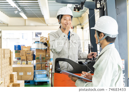 Female worker driving a forklift in a warehouse 74683433