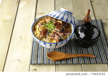 An eel bowl with eel kabayaki on a place mat, a set of soup and a wooden spoon 74683581