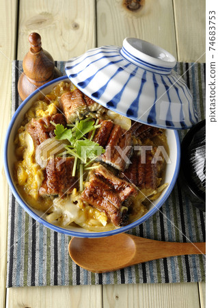 A bird's-eye view of a set of eel bowl, soup and a wooden spoon with eel kabayaki on a place mat 74683753