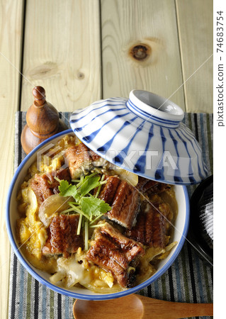 A bird's-eye view of a set of eel bowl, soup and a wooden spoon with eel kabayaki on a place mat 74683754