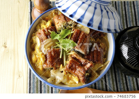 A bird's-eye view of a set of eel bowl, soup and a wooden spoon with eel kabayaki on a place mat 74683756