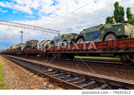 Cargo train carrying military vehicles on railway flat wagons 74685822