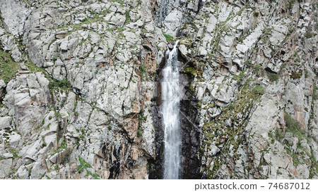 High waterfall among the rocks. View from a drone. High waterfall among the rocks. View from a drone. 74687012