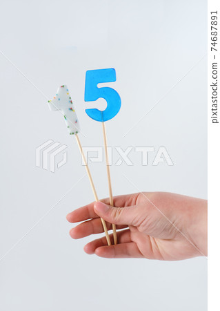 number 15 shaped lolipops in teenager's hand. 74687891