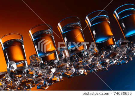 Glasses of vodka with ice on a glass table. 74688633