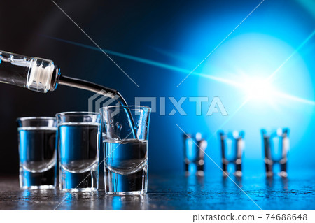 Vodka poured into a glass lit with blue backlight. 74688648