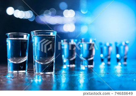 Glasses of Vodka lit with blue backlight. Glasses of Vodka lit with blue backlight. 74688649