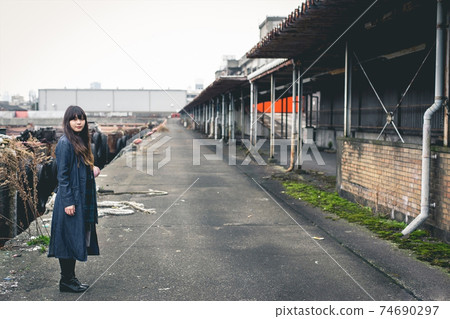 Ruined woman with long hair wearing a long denim jacket looking at the camera Ruined woman with long hair wearing a long denim jacket looking at the camera 74690297