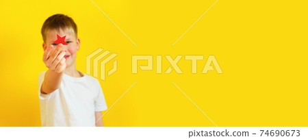 A 6 year old boy holds a red star. The symbol of the army 74690673