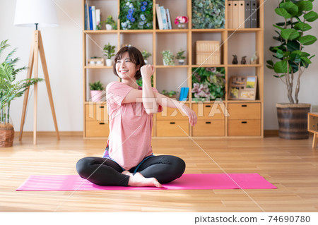 A young woman stretching in the living room 74690780