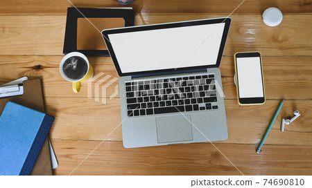 Top view office desk is surrounding by a white blank screen computer laptop and accessories. Top view office desk is surrounding by a white blank screen computer laptop and accessories. 74690810
