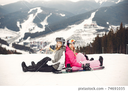 Girls snowboarding in the mountains with the snowboard Girls snowboarding in the mountains with the snowboard 74691035