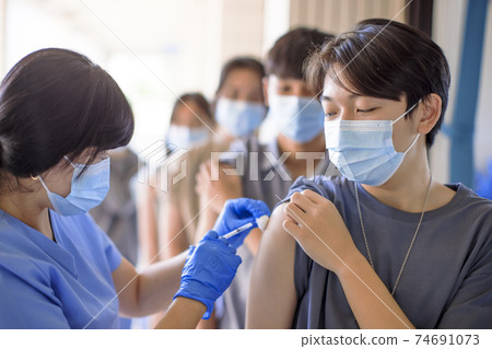 Doctor injecting vaccine for students in high school Doctor injecting vaccine for students in high school 74691073