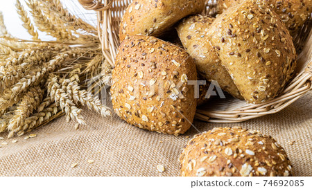 Rustic bread. Fresh loaf of rustic traditional bread with wheat grain ear or spike plant on linen texture background. Rye bakery with crusty loaves and crumbs. Concept - Cooking at Home. Rustic bread. Fresh loaf of rustic traditional bread with wheat grain ear or spike plant on linen texture background. Rye bakery with crusty loaves and crumbs. Concept - Cooking at Home. 74692085