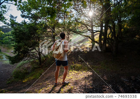 Man Traveler with backpack hiking outdoor in summer sunset forest Man Traveler with backpack hiking outdoor in summer sunset forest 74693338