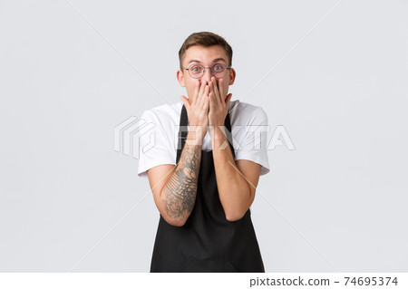 Small retail business owners, cafe and restaurant employees concept. Excited and amazed happy waiter react to amazing news, hold hands over mouth and smiling amused, standing white background Small retail business owners, cafe and restaurant employees concept. Excited and amazed happy waiter react to amazing news, hold hands over mouth and smiling amused, standing white background 74695374