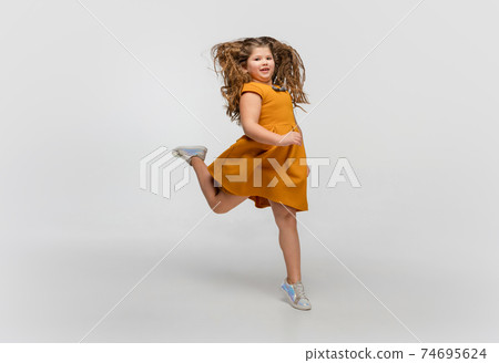 Happy caucasian little girl isolated on studio background. Looks happy, cheerful, sincere. Copyspace. Childhood, education, emotions concept 74695624