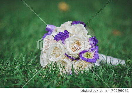 The bride's bouquet. Wedding flower roses. Two wedding rings 74696081