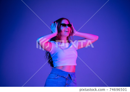 Caucasian woman's portrait isolated on blue studio background in multicolored neon light Caucasian woman's portrait isolated on blue studio background in multicolored neon light 74696501