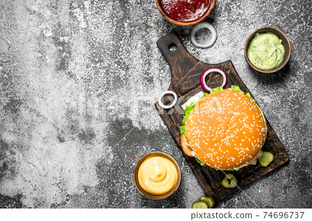 Fresh burger from beef with vegetables and various sauces. Fresh burger from beef with vegetables and various sauces. 74696737