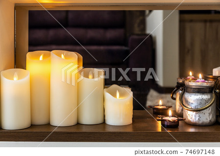 led electric and wax candles stand in the home fireplace. led electric and wax candles stand in the home fireplace. 74697148