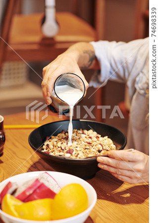 Pouring milk in bowl of muesli Pouring milk in bowl of muesli 74698339