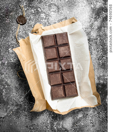 Chocolate bar in a paper wrapper. 74698568