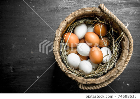 Chicken eggs in a wooden bucket. 74698633