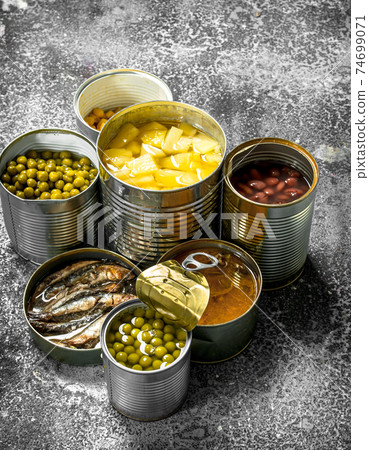 Various canned foods with meat, fish, vegetables and fruits in tin cans. Various canned foods with meat, fish, vegetables and fruits in tin cans. 74699071