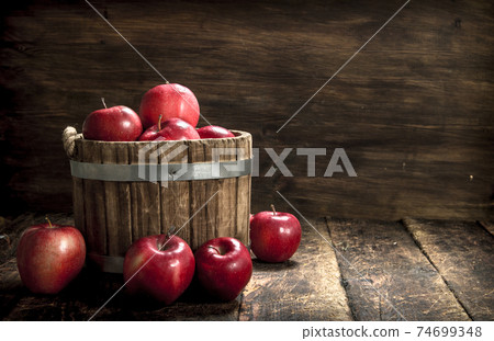 Red ripe apples in a wooden bucket. Red ripe apples in a wooden bucket. 74699348