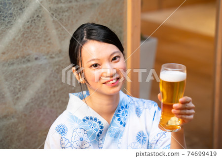 A woman enjoying beer in a yukata 74699419