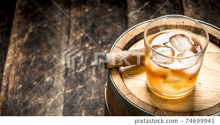 Whiskey background. A barrel of Scotch whiskey with glass and a cigar. 74699941