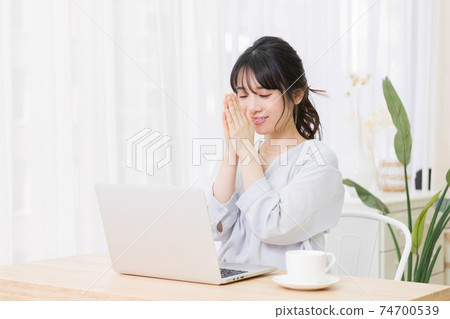一個年輕女子在房間裡使用筆記本電腦時發出請求的手勢 一個年輕女子在房間裡使用筆記本電腦時發出請求的手勢 74700539
