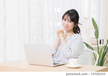 一個年輕女子在房間裡使用筆記本電腦時發出請求的手勢 一個年輕女子在房間裡使用筆記本電腦時發出請求的手勢 74700543