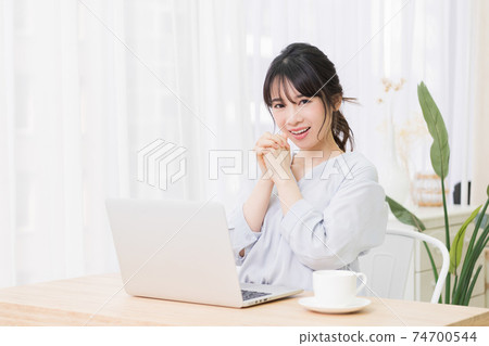A young woman making a request gesture while using a laptop in the room A young woman making a request gesture while using a laptop in the room 74700544